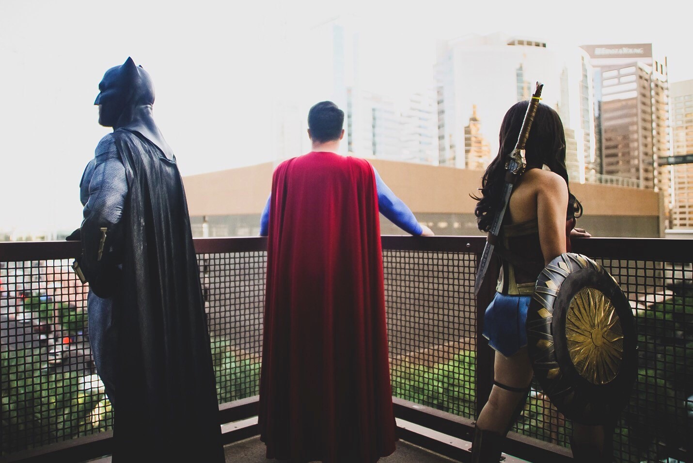 Three costumed superheroes standing on a balcony